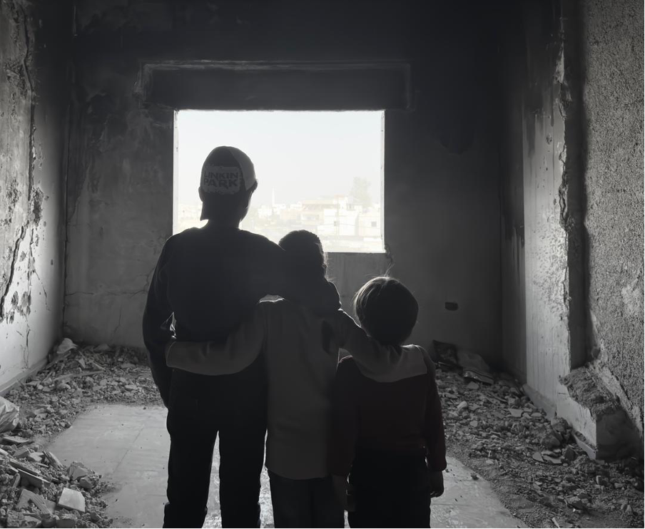 Bambini osservano ciò che resta della loro casa in Siria. Fotografia di Nour Halimah.