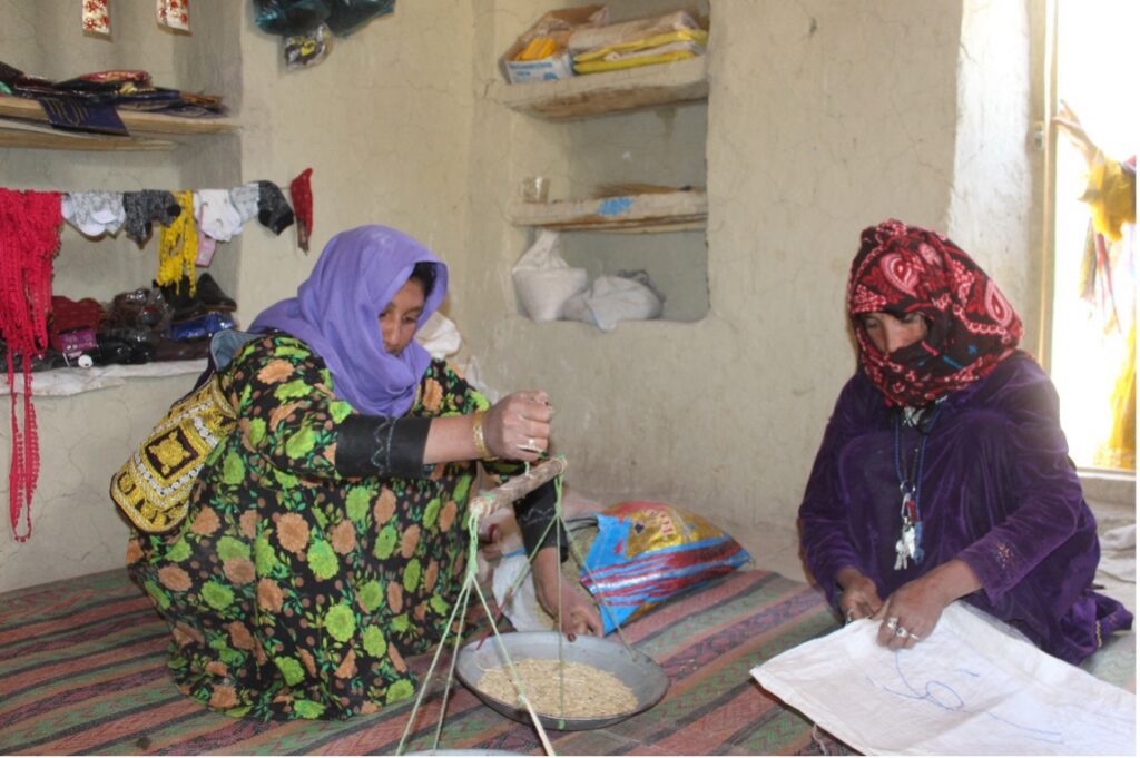 Gulam Bo serve i clienti nell’unico negozio gestito da donne del suo villaggio, aperto con il sostegno di Islamic Relief ai mezzi di sussistenza. Fotografia di Rahmat Nabi Shirzad.